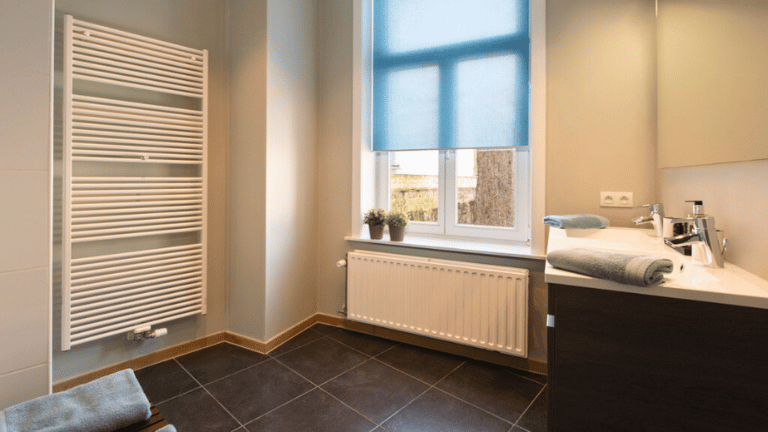 Spacious bathroom in a city center apartment in Bruges with a shower, double sink, hand towels, and toiletries.