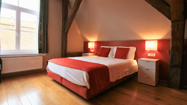 Spacious bedroom in a city center apartment in Bruges with a queen-size bed, large windows, modern furniture, and air conditioning.