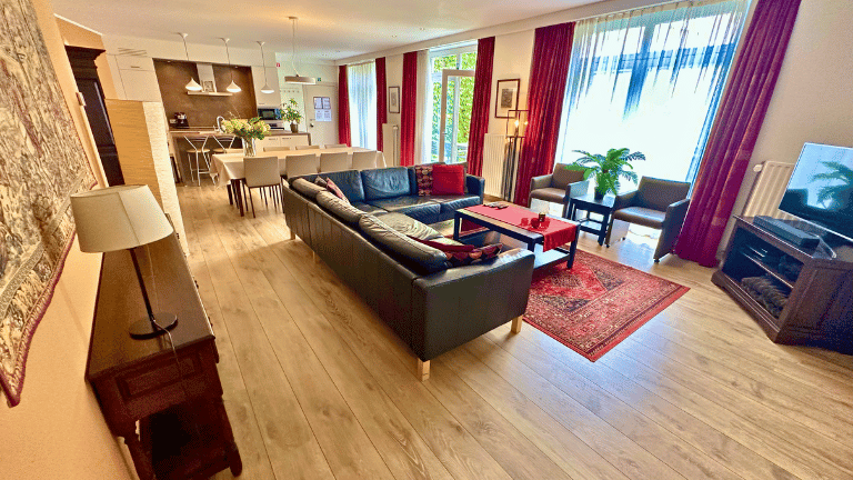 Spacious living room in a city center eight persons holiday rental in Bruges with a dining table, seating area, television, and air conditioning.
