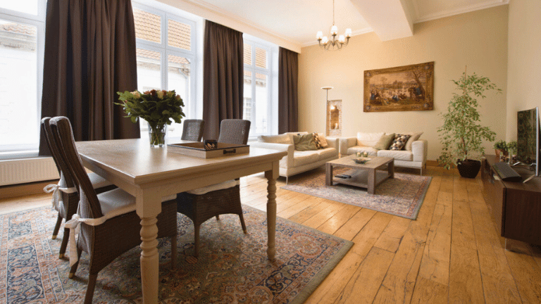 Spacious living room in a city center apartment in Bruges with a dining table, seating area and television.