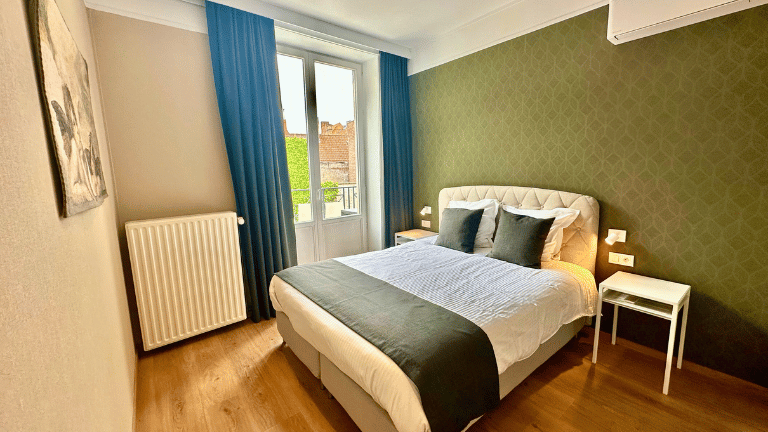 Spacious bedroom in a city center holiday rental in Bruges with a queen-size bed, large windows, modern furniture, and air conditioning. Six persons apartment.